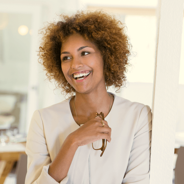 woman laughing and holding her glasses with her hand